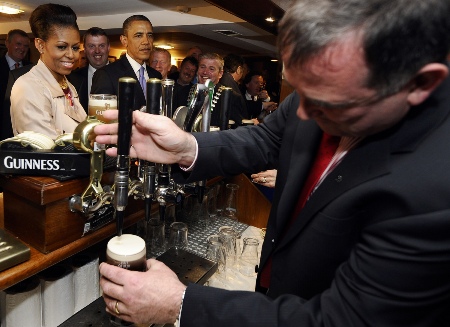US President Barack Obama (C) and First Lady Michelle Obama (L) wait to get their glasses of Guinness in a pub as they visit Moneygall village in rural County Offaly, Ireland, where his great-great-great grandfather Falmouth Kearney hailed from, on May 23, 2011. Obama landed in Ireland on May 23, 2011 for a visit celebrating his ancestral roots, kicking off a four-nation European tour. (JEWEL SAMAD/AFP/Getty Images)