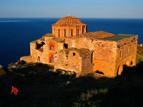 A Belgian tourist walks atop the medieval fortress of Monemvasia in front of the 12th century church of Agia Sophia