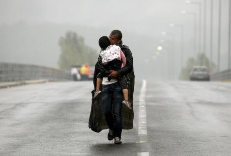 Ένας Σύρος πρόσφυγας φιλά την κόρη του εν μέσω καταιγίδας περπατώντας προς την Ελλάδα στα σύνορα με την ΠΓΔΜ, τον Σεπτέμβριο.